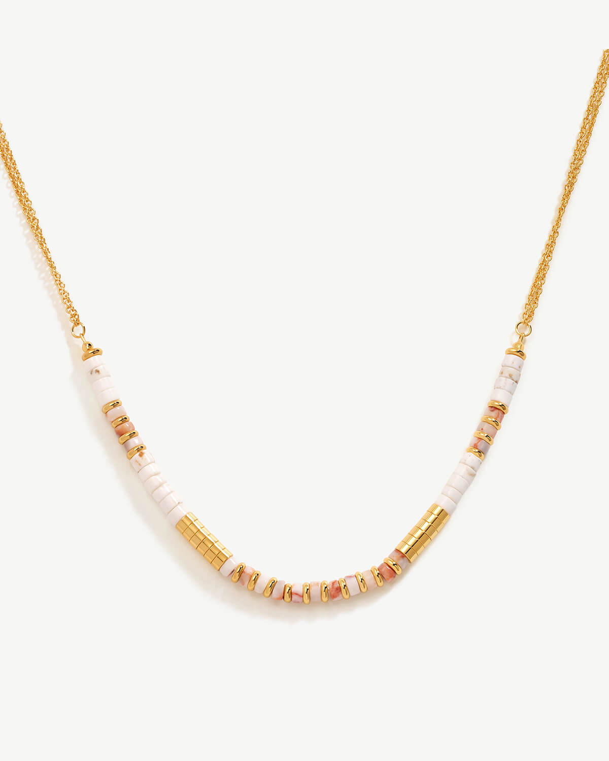 a white and gold necklace on a white background