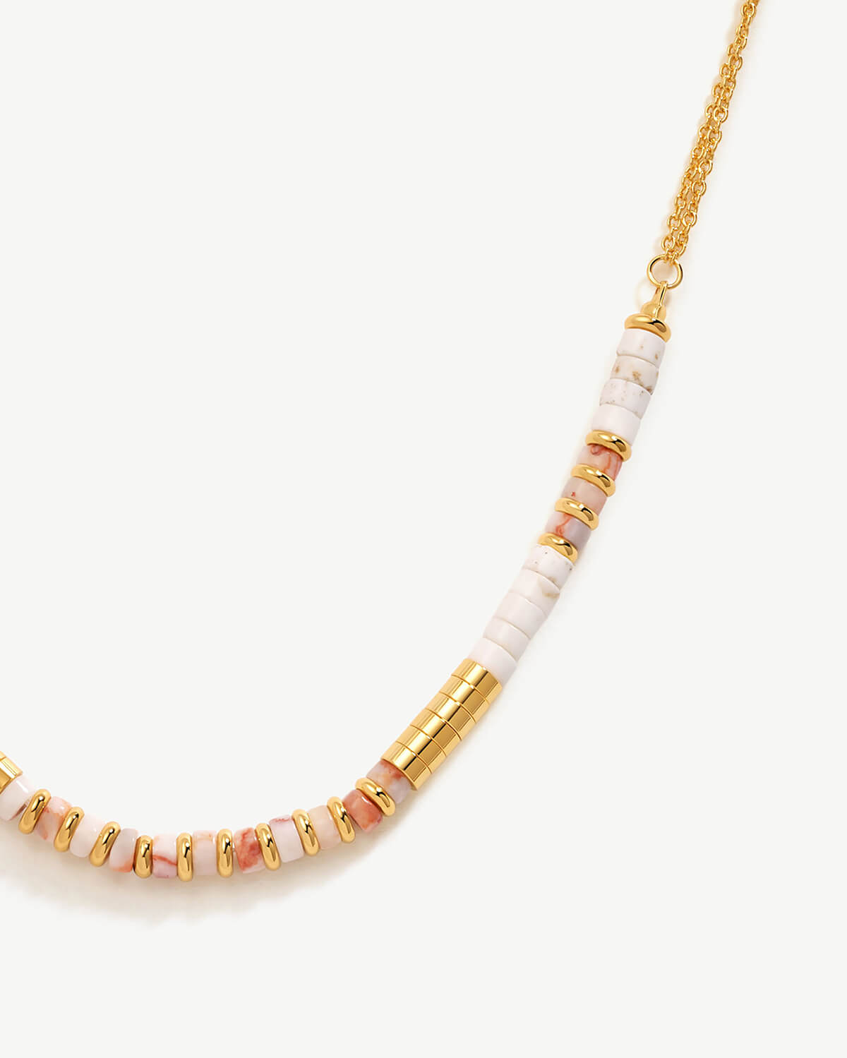 a gold and white necklace on a white background