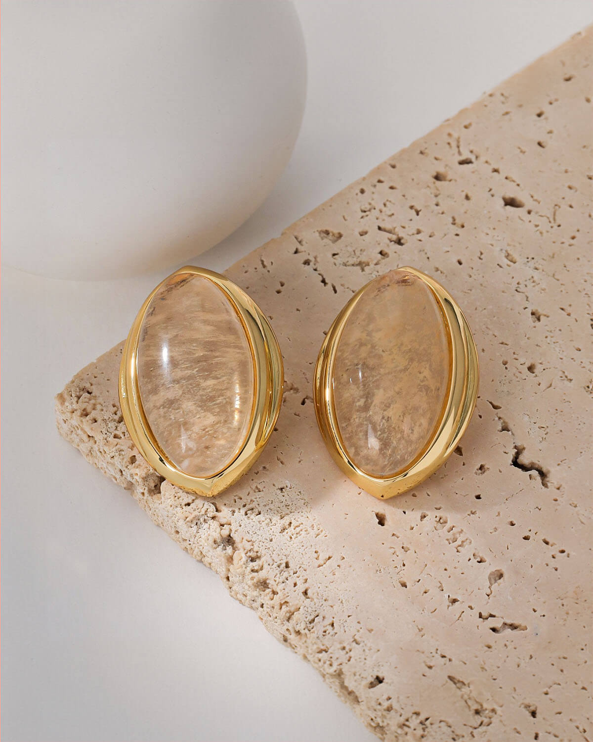 a pair of gold toned earrings with a brown stone