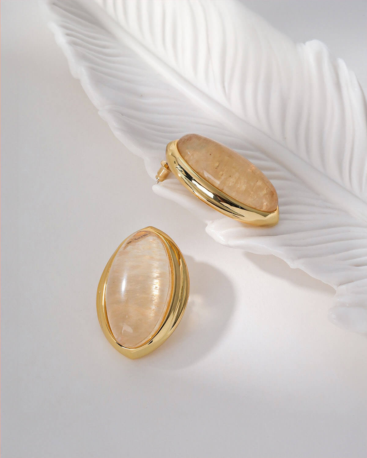 a feather and a ring on a white surface