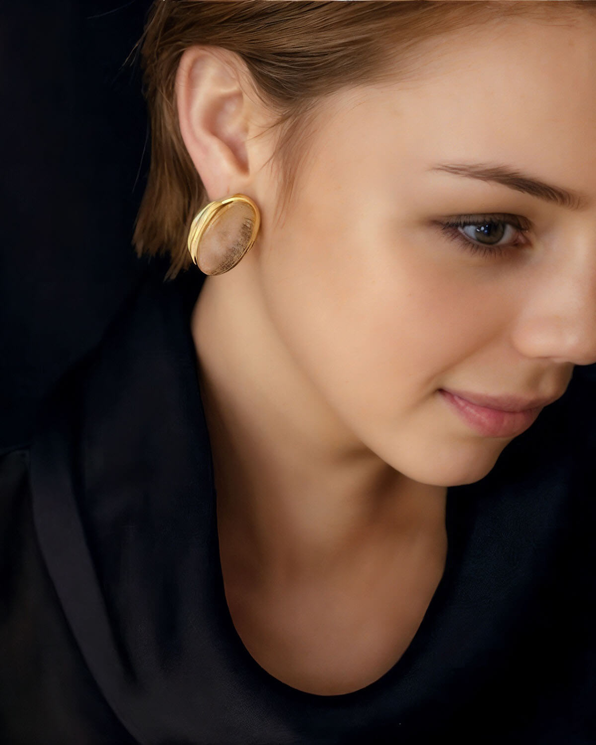 a woman wearing a black shirt and a pair of earrings