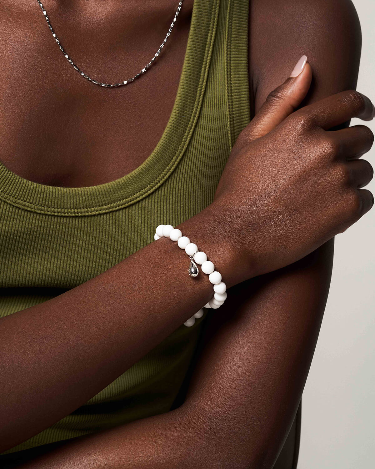 a woman wearing a green tank top and a white beaded bracelet