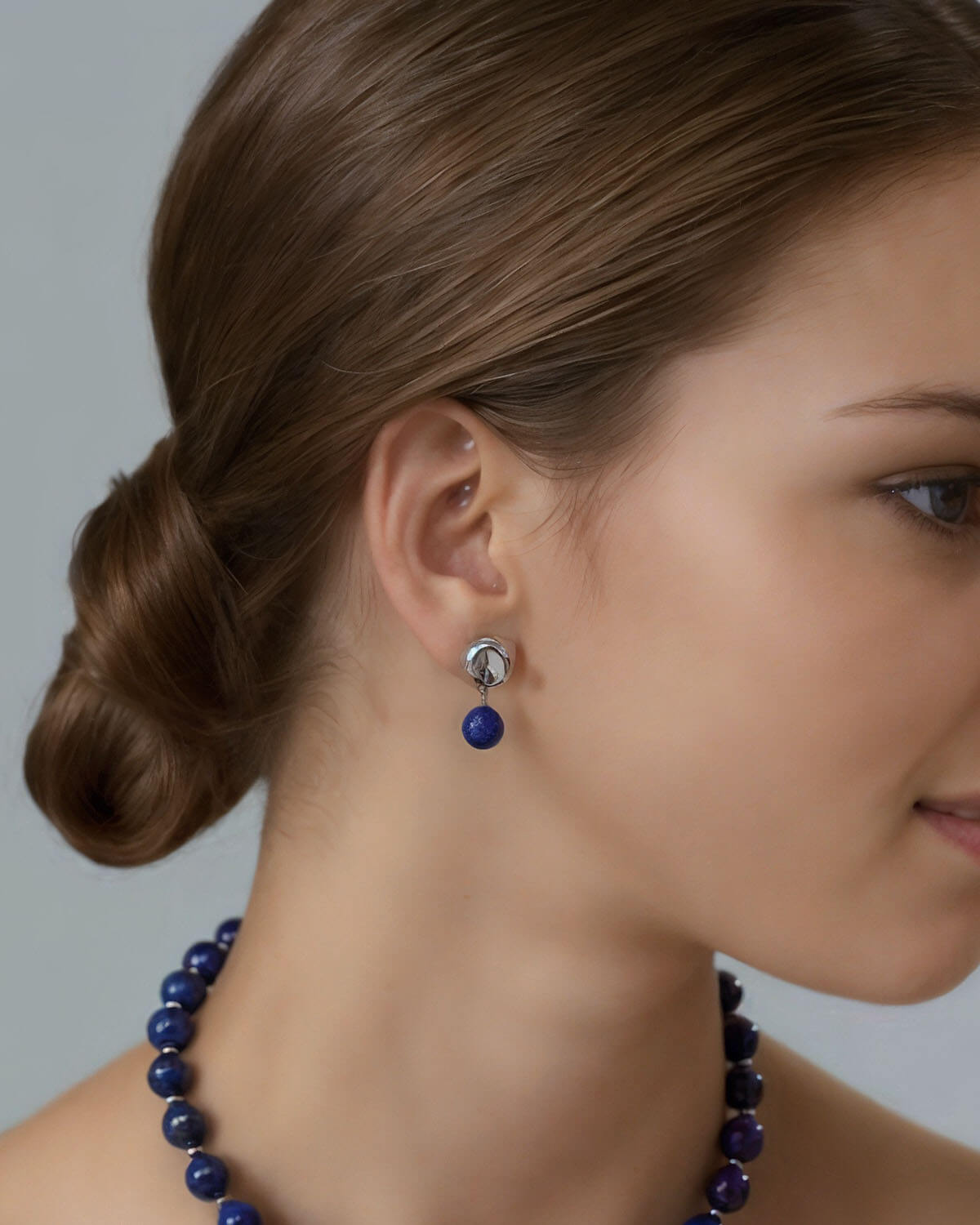 a woman wearing a blue necklace and earrings