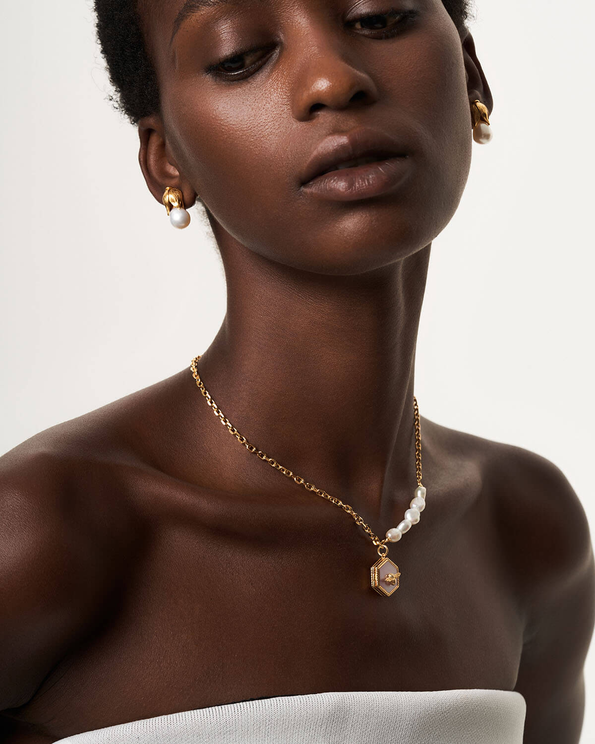 a woman wearing a gold necklace and earrings