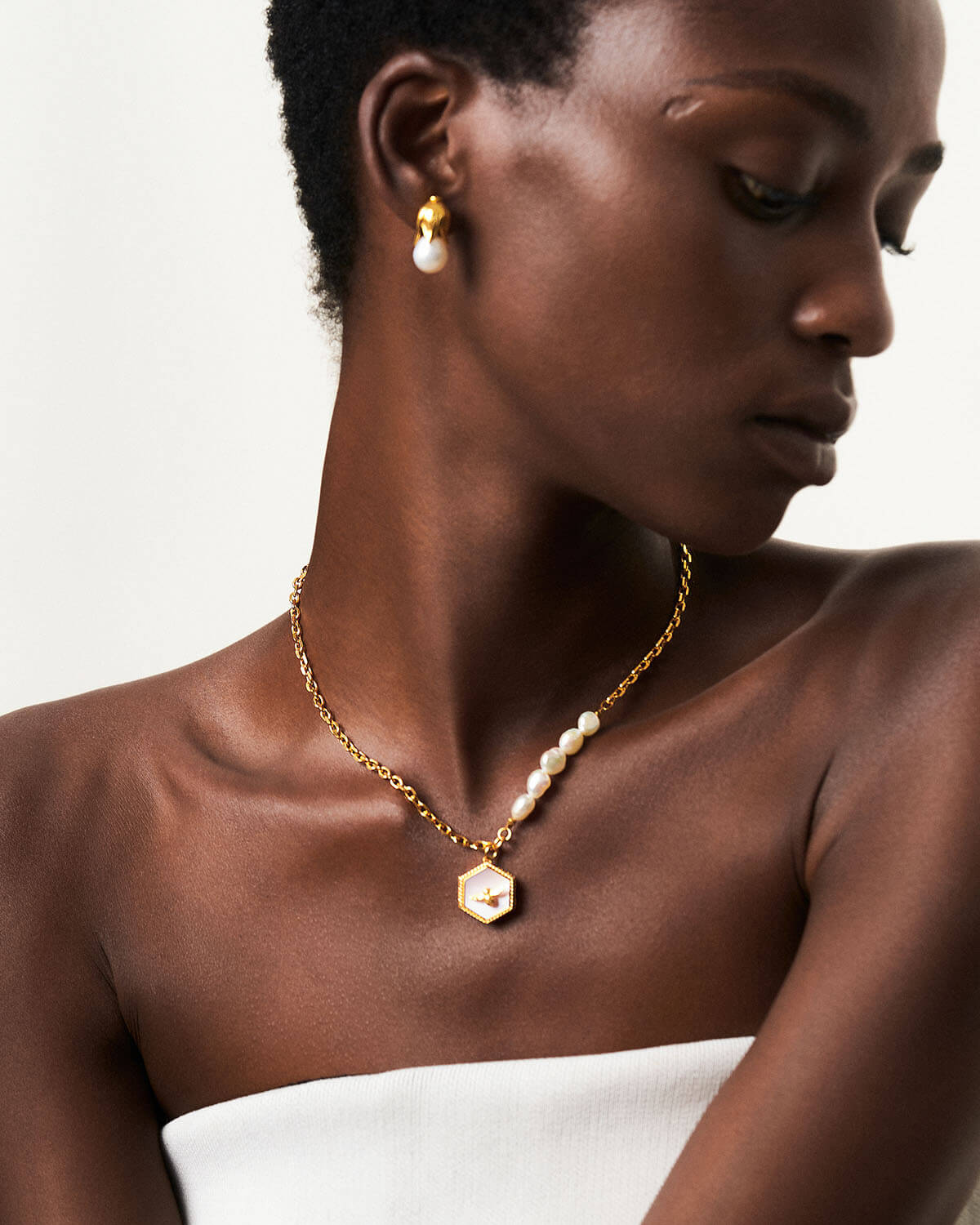 a woman wearing a white dress and a gold necklace