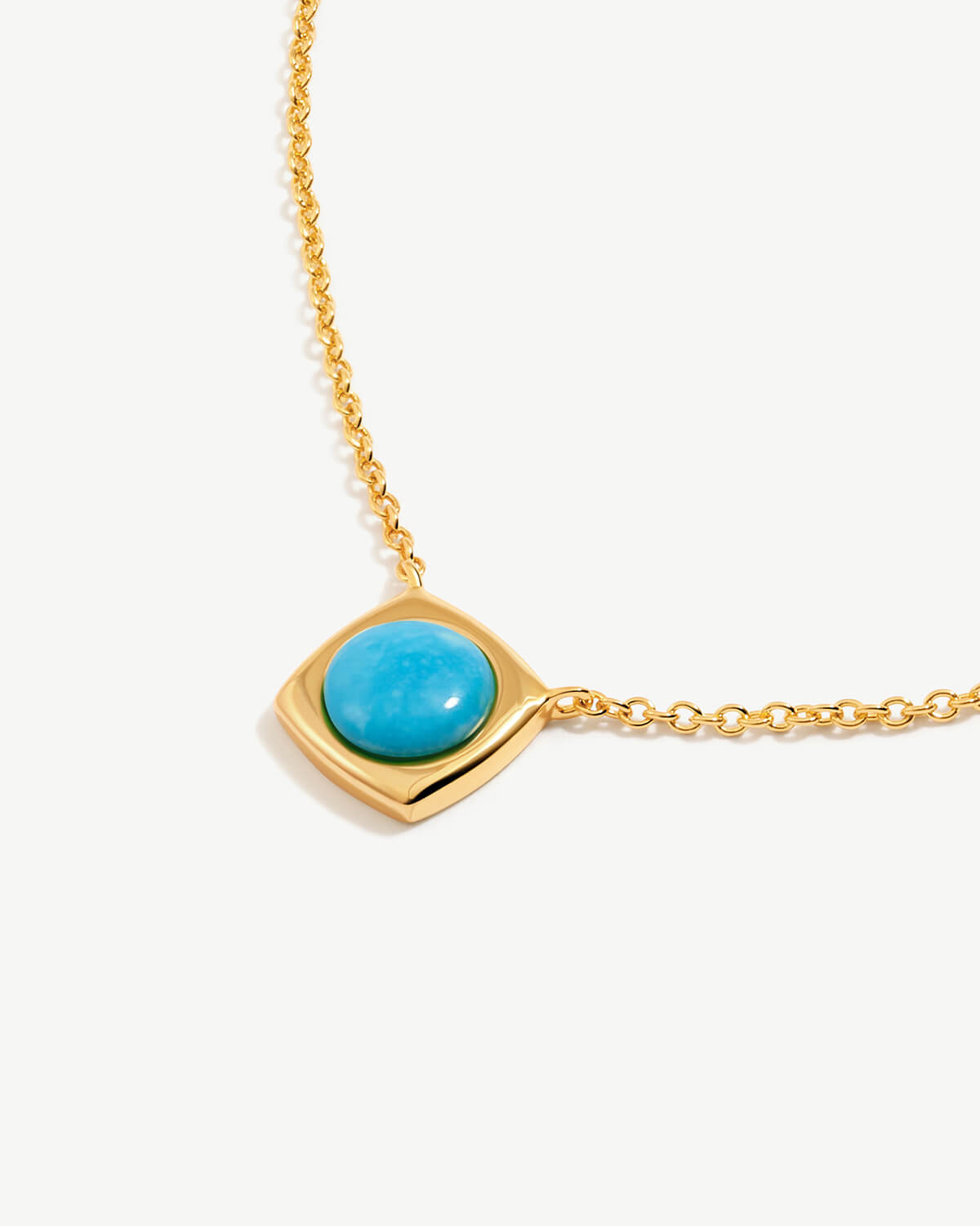 a gold necklace with a turquoise stone on it