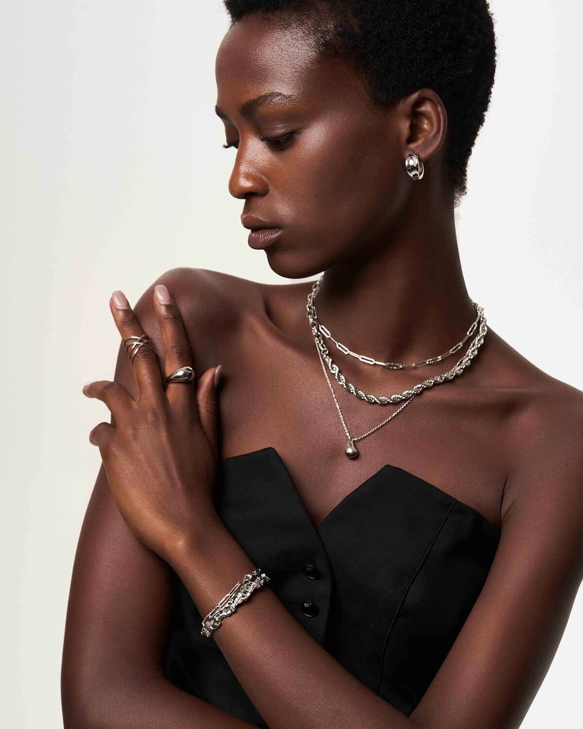 a woman in a black dress wearing a necklace and bracelet