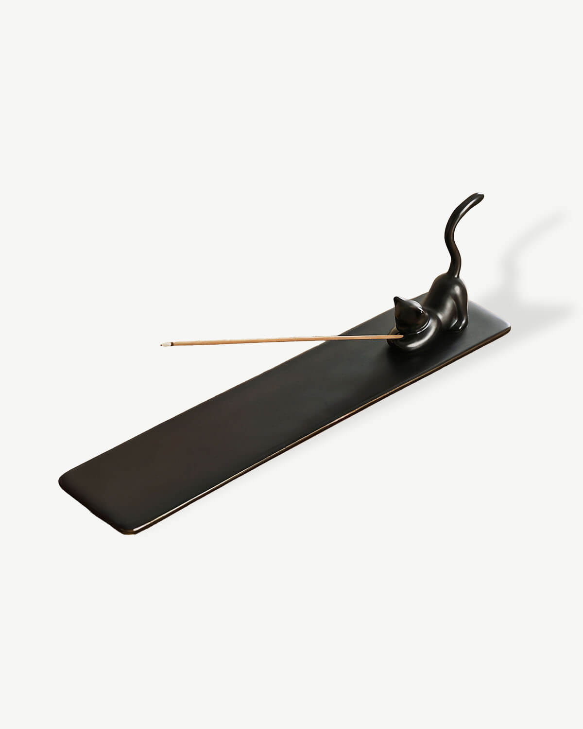 a black incense holder with a cat on top of it