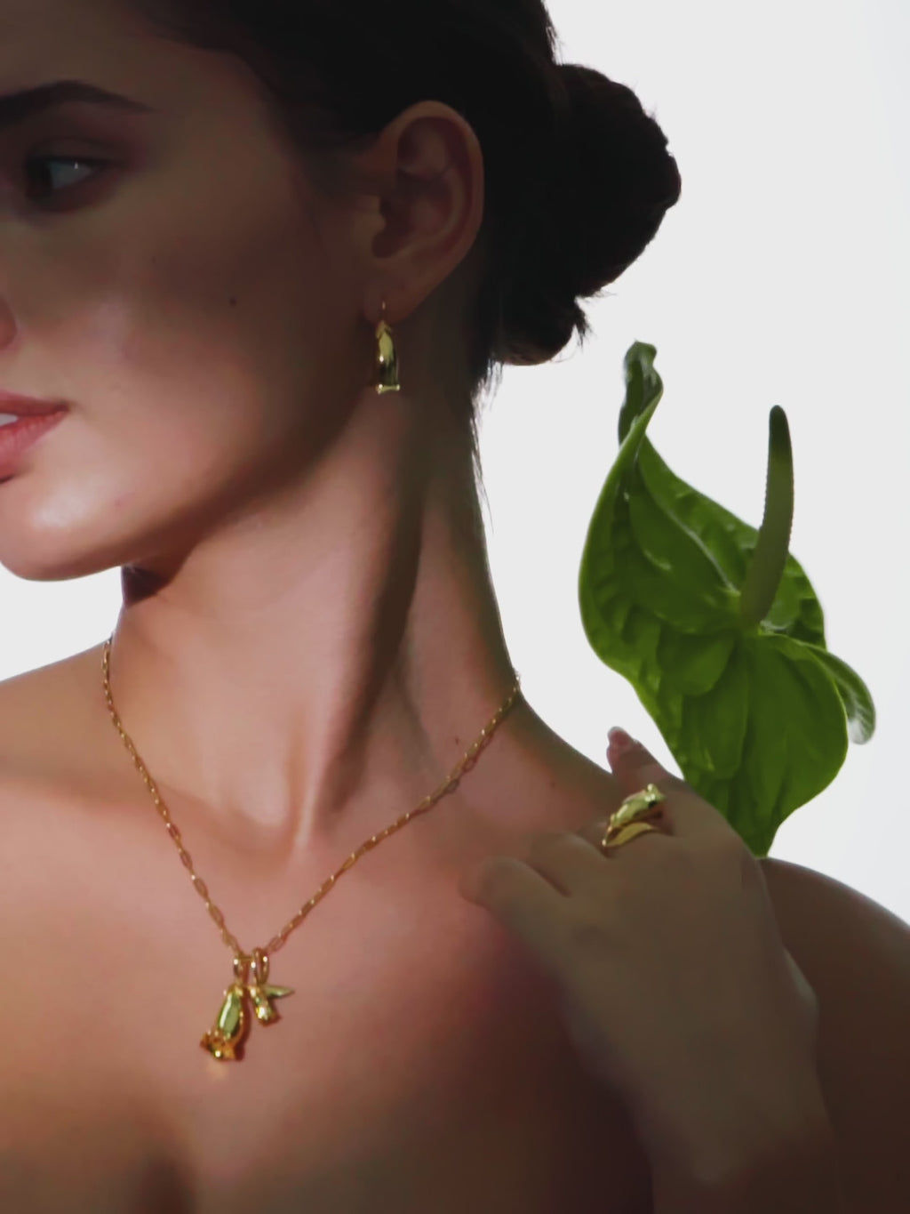 a woman wearing a necklace with a leaf attached to it