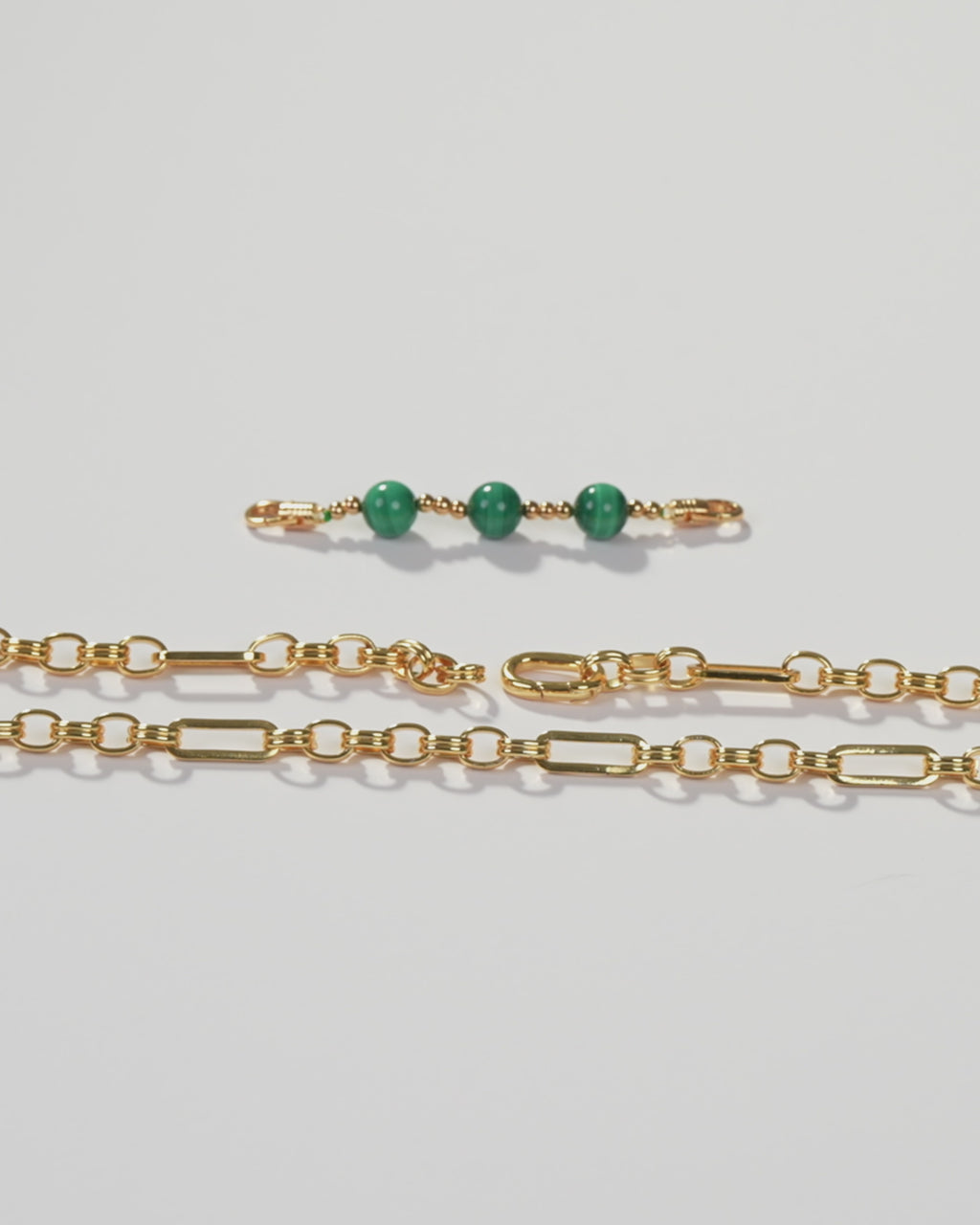 a pair of gold chains with green beads